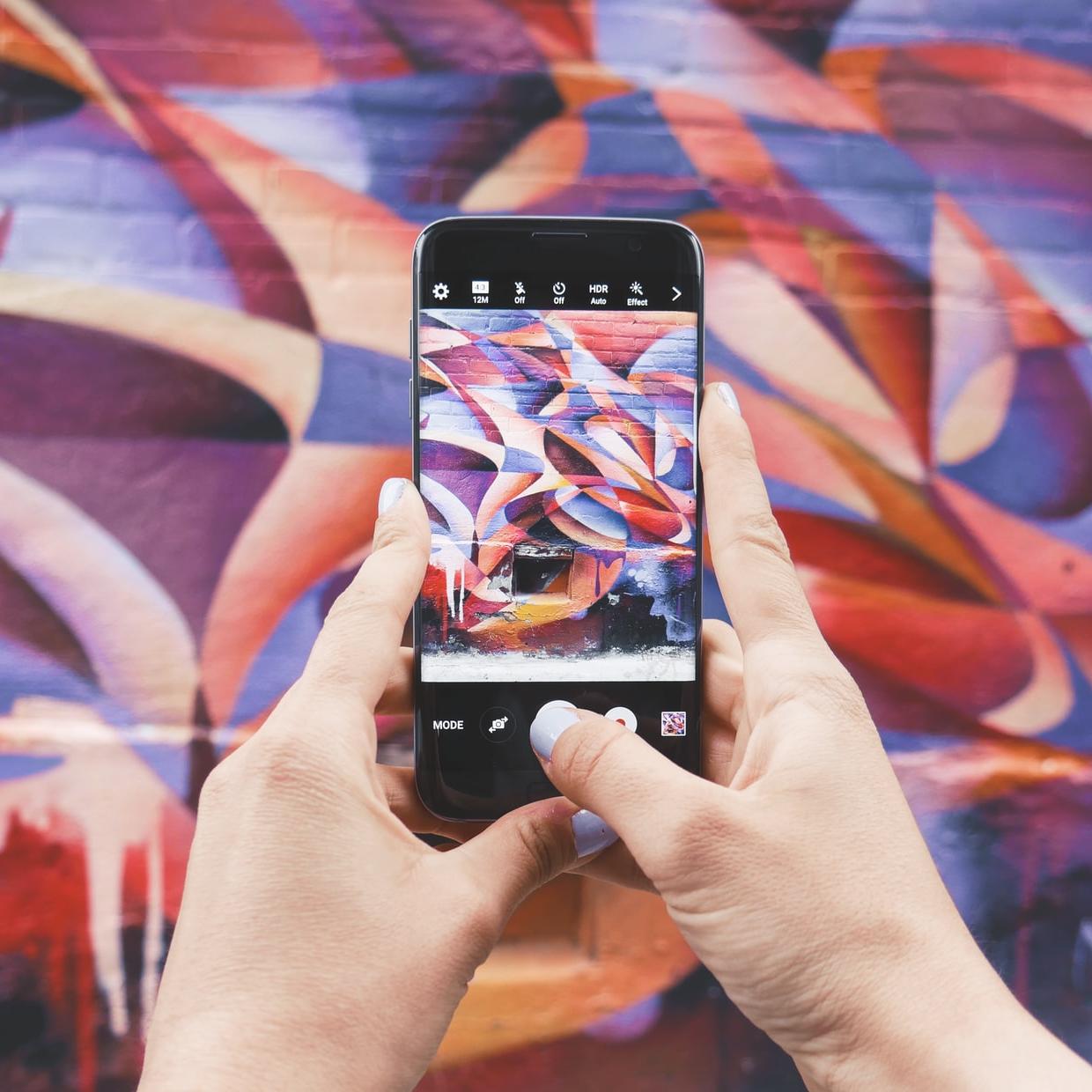 person holding Android smartphone and taking a photo of abstract wall during daytime
